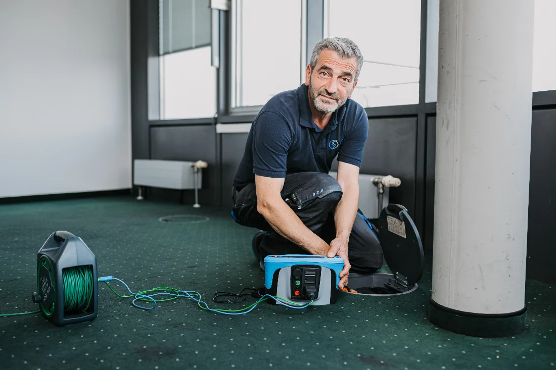 Pruefingenieur fuehrt Thermografie-Messung an offenem Schaltschrank durch